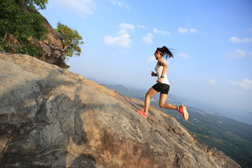 young asian woman runner running on mountain peak