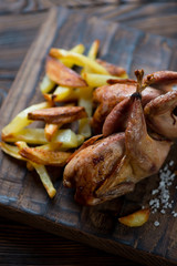 Close-up of baked quails served with potato, selective focus