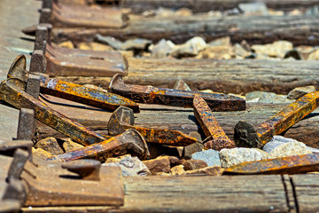 Rusty railroad spikes laying on ground in a pile
