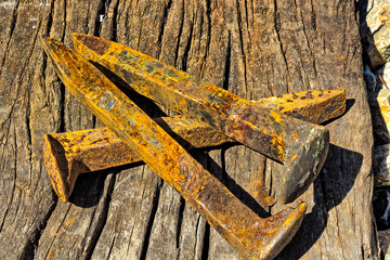 Rusty railroad spikes laying on ground in a pile