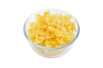 Uncooked bow-tie pasta in glass bowl on light background
