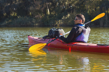 The man is kayaking on the river.