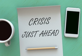 Crisis Just Ahead, message on paper, smart phone and coffee on table, 3D rendering