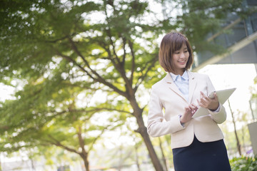 Attractive asian business woman working on tablet computer outsi