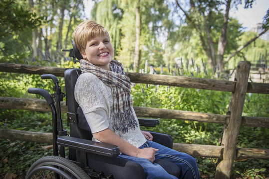 Paraplegic woman in wheelchair smiling in garden