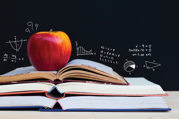Apple on stack of open books with education doodles and copy space. Education concept.