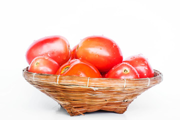Fresh plum tomato in wooden rattan basket on white background