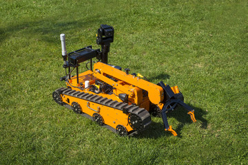 Orange bomb disposal robot folded on the grass