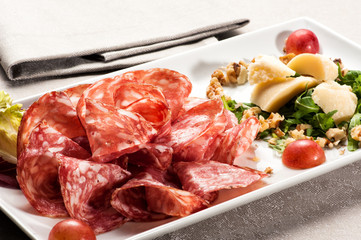 Plate of salami pieces beside parmesean cheese