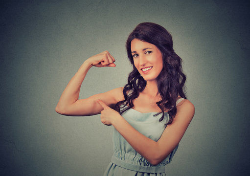 Fit young healthy model woman flexing muscles showing her strength