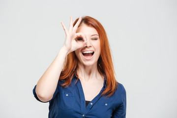 Happy excited woman looking through hole made of fingers