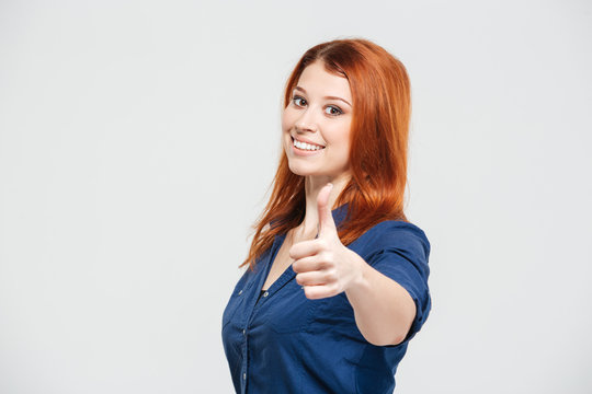 Cheerful attractive redhead young woman showing thumbs up