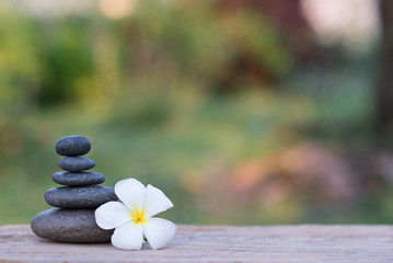white frangipani flower and stone zen spa on wood with garden bl