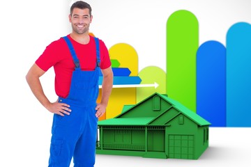 Composite image of happy handyman in overalls with hands on hip