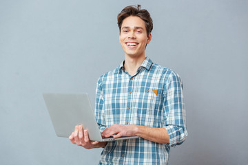 Laughing man standing with laptop computer