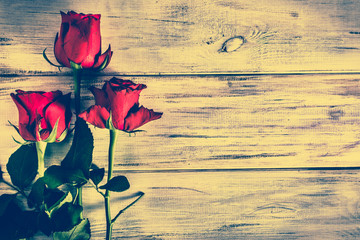 Fototapeta na wymiar Red roses flowers on wood, vintage photo with copy space, overhead