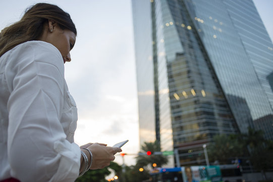 Hispanic businesswoman using cell phone outdoors