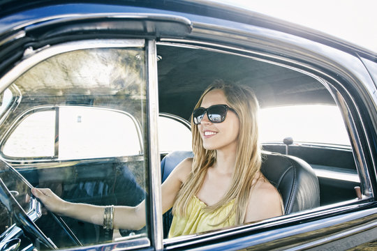 Happy woman driving a vintage car