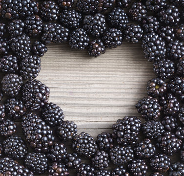 Heart shape made of premium Blackberries on wooden background. Close up, top view, high resolution product