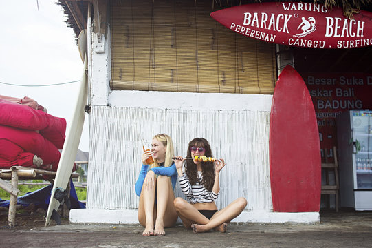 Caucasian women eating at surf hut on beach - Powered by Adobe