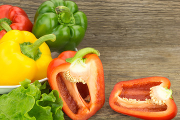 Fresh bell peppers in bowl, on wooden surface.