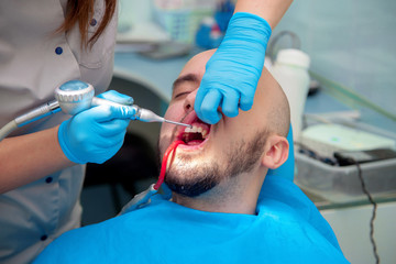 nice young guy treats his teeth in a dental office at the doctor