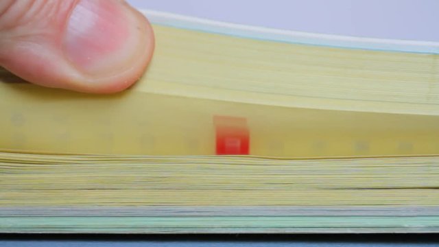 Flipping through pages of a city phone book, close-up