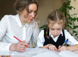 Mother helping daughter with homework at home.