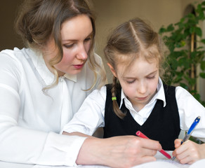 Mother helping daughter with homework at home.