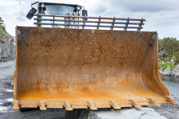 Fototapeta na wymiar Rusty Bucket Excavator lying on the ground on the construction of the road