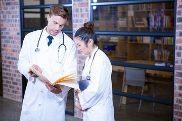 Two doctors looking at file and discussing near library