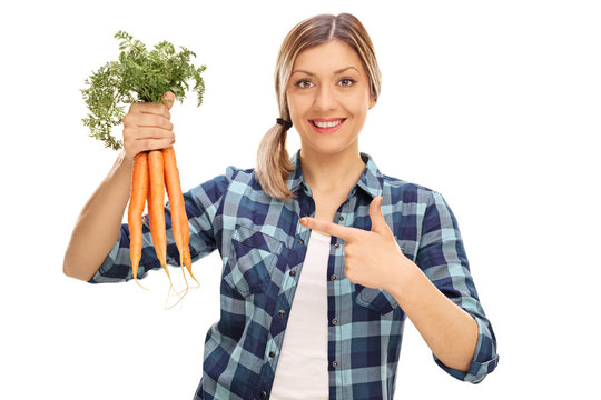 Cheerful woman holding a bunch of carrots