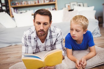 Close-up of father and son reading book at home