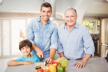 Happy man chopping vegetables with son and father