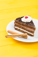 Chocolate cake with cinnamon on a yellow wood table background.