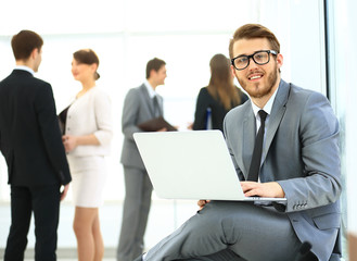 Portrait of a handsome young business man with people in background at office meeting