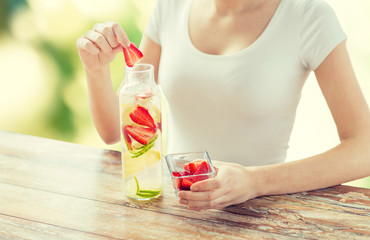 close up of woman with fruit water in glass bottle