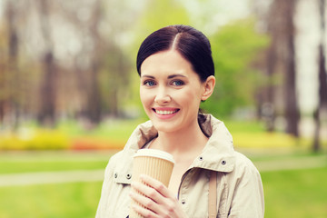 smiling woman drinking coffee in park