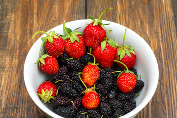 Berries of strawberry and mulberry on wooden table
