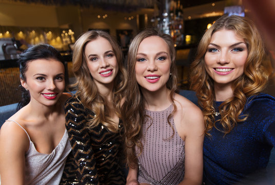 happy smiling women taking selfie at night club