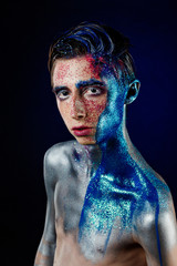 Crazy young androgyne man with face art. SPACEMAN. Freak person. Tinsel creative blue makeup....