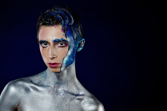 Crazy young androgyne man with face art. SPACEMAN. Freak person. Tinsel creative blue makeup. Intersex and anorexia concept. Space for logo