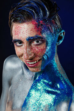 Crazy young androgyne man with face art. SPACEMAN. Freak person. Sperm on face. Tinsel creative blue makeup. Intersex and anorexia concept. Space for logo