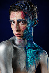 Crazy young androgyne man with face art. SPACEMAN. Freak person. Tinsel creative blue makeup. Intersex and anorexia concept. Space for logo. HOMOSEXUALITY