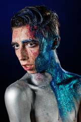 Crazy young androgyne man with face art. SPACEMAN. Freak person. Tinsel creative blue makeup....