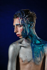 Crazy young androgyne man with face art. Freak person. Sperm on face. Tinsel creative blue makeup....