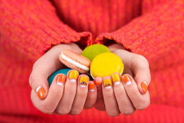Female hands with manicure holding macaroon cookies