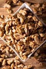 White bowl on wooden board full of walnuts