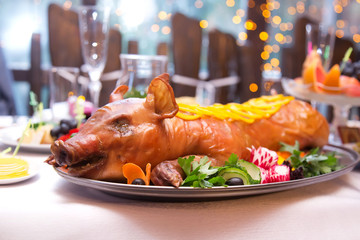 Roast pig. Roasted piglet with vegetables on platter