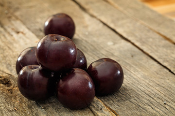 Bunch of round plums set on old wooden surface